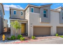 Charming townhome with a two-car garage, yellow front door and low-maintenance landscaping at 2691 Mango Light Ave, North Las Vegas, NV 89086