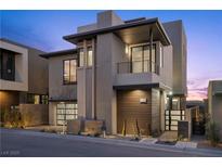 Modern two-story home featuring sleek design, wood accents, a balcony, and manicured landscaping at 577 Overlook Rim Dr, Henderson, NV 89012