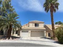 Charming two-story home features a three-car garage, tile roof, and mature palm trees in a desert landscape at 8432 Apple Hill Ct, Las Vegas, NV 89128