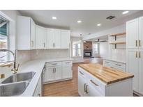 Bright kitchen with white cabinets, gold hardware, quartz countertops, and stainless steel sink at 2107 Fountain Springs Dr, Henderson, NV 89074
