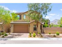 Inviting two-story home featuring a brick driveway, tan exterior, and a well-manicured lawn at 419 Vigo Port St, Las Vegas, NV 89138