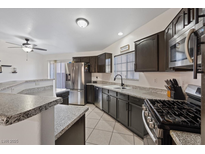 Modern kitchen featuring stainless steel appliances and dark cabinetry with granite countertops at 5184 Mineral Lake Dr, Las Vegas, NV 89122
