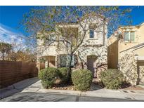 Inviting two-story home featuring a neutral color scheme, manicured bushes, and a quaint front porch at 7491 Speedwell Cavern St, Las Vegas, NV 89139
