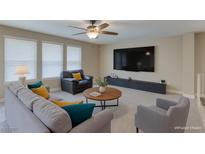 Relaxing living room featuring neutral colors, a ceiling fan, plush seating, and a large television at 9469 Coral Shine Ct, Las Vegas, NV 89123