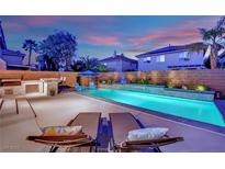 Outdoor pool featuring water features, custom patio, and an outdoor kitchen area create a backyard oasis at 10902 Fintry Hills St, Las Vegas, NV 89141