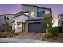 Modern two-story home with a two-car garage, desert landscaping, and a brick driveway at 2004 Peaceful Mesa Ct, Henderson, NV 89052