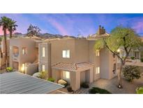 Tan stucco condo building featuring a tile roof, desert landscaping, and mountain views at 2200 Highpointe Dr # 202, Laughlin, NV 89029