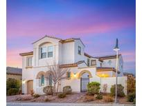 Elegant two-story home boasting a white exterior, arched entry, and tile roof against a colorful evening sky at 352 Dandelion Brook Ct, Las Vegas, NV 89148