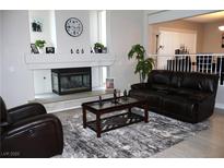 Cozy living room with a decorative fireplace, a dark leather couch, and a stylish area rug at 1680 Sweet Pea Ave, Las Vegas, NV 89183