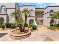 Exterior view of a stucco apartment building with arched windows and well-maintained landscaping at 3150 Soft Breezes Dr # 1216, Las Vegas, NV 89128
