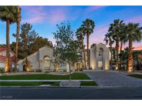 Elegant single-story home with lush landscaping, palm trees and a circular driveway at 2268 Buckingham Ct, Henderson, NV 89074