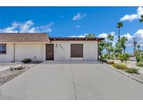 Tan single-story home with simple landscaping and a concrete driveway under a partly cloudy sky at 2635 Heritage Ct, Las Vegas, NV 89121