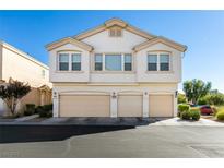 Inviting townhouse featuring a three-car garage and cream-colored facade under a clear blue sky at 6549 Clara Bow Ave # 103, Las Vegas, NV 89122