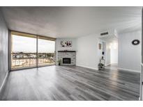 Bright living room featuring a stone fireplace, large windows with city views, and stylish gray wood flooring at 745 N Royal Crest Cir # 141, Las Vegas, NV 89169