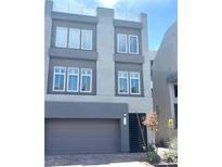 Contemporary gray three-story home featuring a garage, rooftop deck, and manicured front yard at 8095 Carpenter Creek Ave, Las Vegas, NV 89113