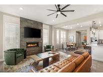 Open-concept living room with stone fireplace, flatscreen TV, and modern furnishings, seamlessly flowing into the dining area at 11280 Granite Ridge Dr # 1012, Las Vegas, NV 89135