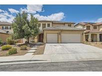 Charming two-story home featuring a tile roof, a three-car garage, and a manicured front yard with mature trees at 6329 Orange Hue St, North Las Vegas, NV 89031