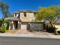 Two-story home showcasing a two-car garage, brick driveway, and beautiful landscaping at 640 House Blend Ln, Henderson, NV 89052