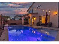 Backyard pool area illuminated with string lights, and lounge seating, perfect for evening relaxation at 9917 Fletcher Peak Ave, Las Vegas, NV 89178
