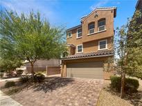 Two-story home featuring an attached garage, brick driveway, and landscaped front yard at 148 Campbelltown Ave, Henderson, NV 89015