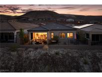 Charming home exterior with a cozy patio and mountain views at twilight at 174 Cabo Cruces Dr, Henderson, NV 89011