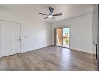 Bright living room with wood-look floors, white walls, ceiling fan, and sliding glass door to a balcony at 2110 Los Feliz St # 1003, Las Vegas, NV 89156
