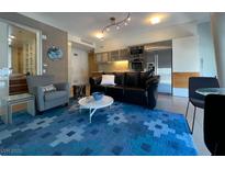 Modern living room featuring a blue rug, black sofa, and stainless steel kitchen appliances at 3722 Las Vegas Blvd # 2709, Las Vegas, NV 89158