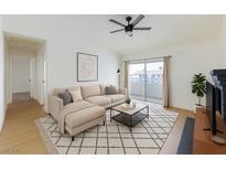 Bright living room features a modern ceiling fan, neutral-toned sofa, and sliding glass doors to a balcony at 3770 Shirebrook Dr # 160, Las Vegas, NV 89115