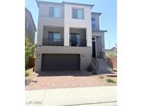 Two-story home featuring a balcony, two-car garage, and brick paved driveway at 7499 Lodano Ave, Las Vegas, NV 89113