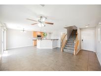 Open-concept living room featuring tile floors, modern ceiling fan and staircase leading to the upper level at 1180 Via Vinci, Henderson, NV 89052