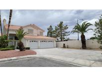 Two-story home featuring a three-car garage, desert landscaping and a red tile roof at 1211 Silver Knoll Ave, Las Vegas, NV 89123