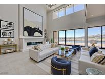 Bright living room boasts high ceilings, modern fireplace, and expansive windows with lake views at 1600 Pleasant Bay Ct, Henderson, NV 89011