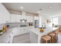 Bright kitchen with stainless steel appliances, white cabinets, and marble countertops and backsplash at 3065 Blue Monaco St, Las Vegas, NV 89117