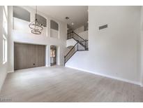 Bright, open-concept living room with wood floors, high ceilings, and a decorative chandelier at 3065 Blue Monaco St, Las Vegas, NV 89117