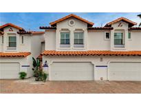 Charming townhome exterior with a brick driveway, white facade, and terracotta roof tiles at 8719 Villa Ariel Ln, Las Vegas, NV 89147