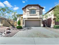 Two-story stucco home with a paver driveway, arched entry, and a two-car garage in a suburban neighborhood at 10056 Cranbrook Falls Ct, Las Vegas, NV 89148
