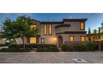 Charming stucco home with a brick walkway, manicured bushes, and inviting curb appeal at 2435 Granada Bluff Ct, Las Vegas, NV 89135