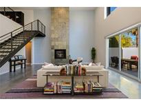Bright, open living room with a modern fireplace, high ceilings, and staircase at 2672 Mystere Ct, Las Vegas, NV 89117