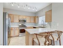 Bright kitchen featuring stainless steel appliances, light wood cabinets, and a breakfast bar with seating at 3930 Legend Hills St # 102, Las Vegas, NV 89129
