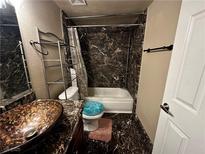Bathroom with marble-style wall covering, single sink, and shower over tub at 5188 River Glen Dr # 453, Las Vegas, NV 89103
