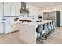 Modern kitchen with white cabinets, stainless steel appliances, and a large marble island with seating at 5321 Brayden Ct, Las Vegas, NV 89131