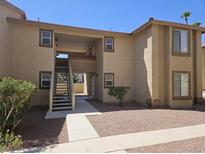 Tan two-story condo building with red rock landscaping, a staircase to the second floor, and an open entryway at 7300 Pirates Cove Rd # 2025, Las Vegas, NV 89145