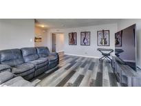 Inviting living room featuring wood-style flooring, a gray sofa, and vibrant guitar wall art at 100 Huntly Rd, Las Vegas, NV 89145