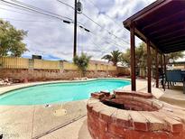 Backyard pool with a brick fire pit and an outdoor dining area under a covered patio at 4881 E Imperial Ave, Las Vegas, NV 89104