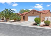 Single-story home featuring a terracotta roof, palm trees, an attached two-car garage, and well-maintained landscaping at 608 Blooming View Ave, North Las Vegas, NV 89032