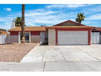 Single-story home featuring a two-car garage, desert landscaping, and a red and beige exterior at 1158 E Hacienda Ave, Las Vegas, NV 89119