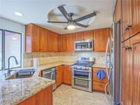 Well-lit kitchen with stainless steel appliances, wooden cabinets, and granite countertops at 2462 Pickwick Dr, Henderson, NV 89014