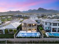 Beautiful aerial view of a two story home with a pool and outdoor seating with mountain views in the background at 390 Coastal Redwood St, Las Vegas, NV 89138
