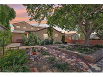 Charming home with a beautifully landscaped front yard featuring brickwork, lush greenery, and mature shade trees at 639 I Ave, Boulder City, NV 89005