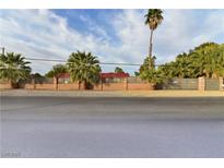 View of the property with palm trees, red roofing and a decorative, light brick perimeter fence at 2926 E Eldorado Ln, Las Vegas, NV 89120